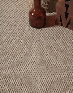 a brown bottle sitting on top of a rug next to a wooden sign and vase