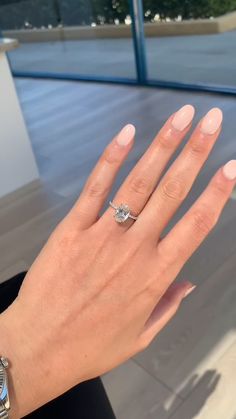 a woman's hand with a diamond ring on top of her left hand, in front of a window