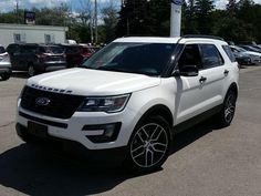 a white ford explorer is parked in a lot with other cars and trucks behind it