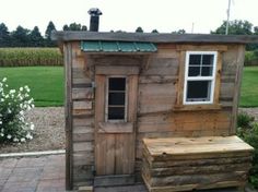 a small wooden shed with a bench in front of it and a window on the side