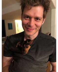 a man is holding a small dog in his lap and smiling at the camera,