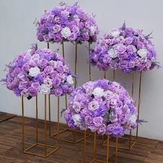 purple and white flowers are arranged on gold stands