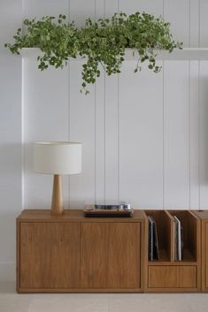 a wooden cabinet with a plant hanging from it's side and a lamp next to it