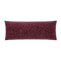 the burgundy velvet pillow is embroidered with an intricate floral design on it's side