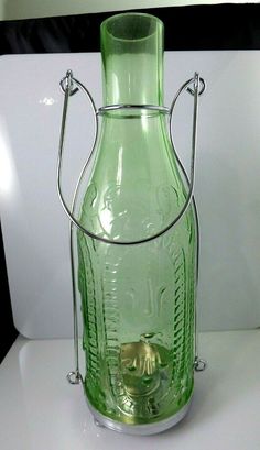 a green glass vase sitting on top of a white table