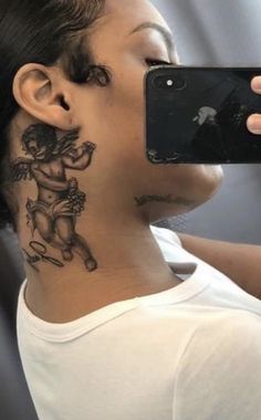 a woman taking a selfie with her cell phone in front of her neck tattoo