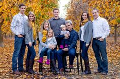 a group of people standing next to each other in front of trees with leaves on the ground