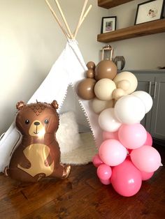 some balloons are on the floor near a teepee tent and a teddy bear balloon