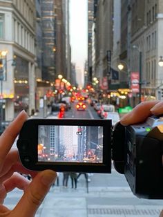 someone holding up a camera to take a picture on the street with other people in the background