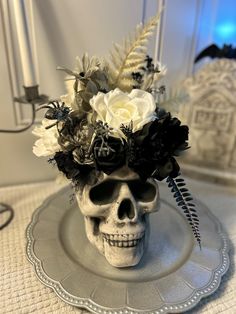 a skull with flowers in it sitting on a plate