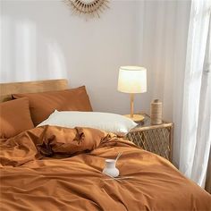 a bed with an orange comforter and two white lamps on the side tables next to it