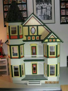 a large doll house with pictures on the wall behind it