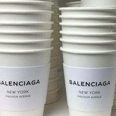 several white cups stacked on top of each other in front of a wall with the words baleinciaca written on them