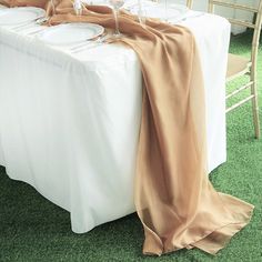 the table is set with two wine glasses and an orange cloth draped over it, along with gold chairs