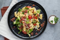 a black plate topped with pasta salad and dressing