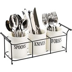 three white cups with spoons and forks in them on a black metal holder holding utensils