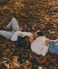 a man and woman laying on the ground surrounded by leaves