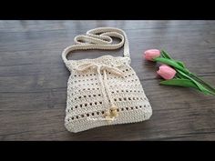 a crocheted purse sitting on top of a wooden floor next to tulips