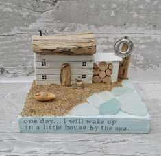 there is a small house made out of wood and sand on the beach with words written below it