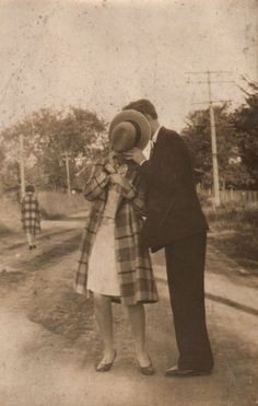 an old black and white photo of two people standing on the side of a road