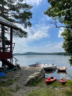 several small boats are parked on the shore near a dock and water way with a boathouse in the background