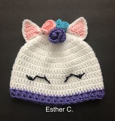 a crocheted hat with a cat's face on it and a flower in the middle