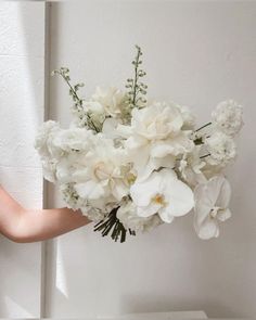 a woman holding a bouquet of white flowers