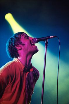 a man singing into a microphone while standing in front of a light on a stage