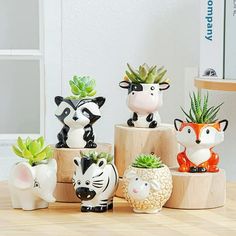 small ceramic animal planters are sitting on a wooden table with succulents and cacti