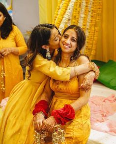 two women in yellow dresses hugging each other