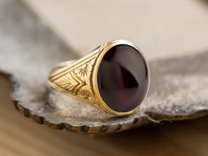 A beautiful signet ring with carvings on the sides made by hand and garnet gemstone in the center. *real images of the ring, taken by us* Garnet Stone Size: 14x12mm Material: - Sterling Silver 925 - 9K Gold (375) - 14K Gold (585) - 18K Gold (750) *All signet rings are hallmarked on the back for certification* - We offer FREE Worldwide DHL & FedEx Shipping! - Branded DanelianJewelry Gift Box with each order! Our customer service is available 7 days a week. Leave us your message, and we will get b Garnet Ring Men, Garnet Gemstone Signet Ring, Formal Garnet Signet Ring, Antique Hallmarked Ruby Signet Ring, Classic Oval Engraved Ruby Ring, Vintage Garnet Rings With Polished Finish, Heirloom Signet Ring With Cabochon As A Gift, Heirloom Signet Ring With Cabochon For Gift, Heirloom Ruby Signet Ring With Polished Finish