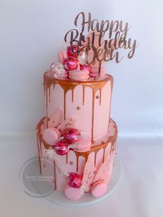 a three tiered cake with pink frosting and chocolate drips on the top