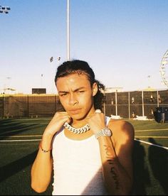 a woman standing on top of a tennis court wearing a white tank top and bracelet