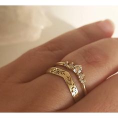 a person's hand with a gold ring on top of it and two diamonds in the middle