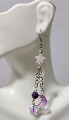 Charming Handmade Pink and Purple Stars and Moons Dangle Earrings Lend an element of dreamy allure to your ensemble with these handmade dangle earrings, displaying a captivating motif of pink and purple stars and moons. Assembled with the highest quality surgical stainless steel, these earrings epitomize unmatched durability. Their nickel-free anatomy ensures a worry-free wear experience even for those with sensitive skin. These dangle earrings, being not only visually appealing but also incredi Star Jewelry Diy, Handmade Purple Celestial Earrings, Celestial Purple Dangle Earrings, Purple Celestial Dangle Earrings, Pink Star-shaped Sterling Silver Jewelry, Pink Dangling Charms Drop Earrings, Pink Drop Earrings With Dangling Charms, Pink Star Charm Dangle Earrings, Pink Dangle Earrings With Star Charm