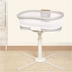 a baby crib sitting on top of a wooden floor next to a white chair