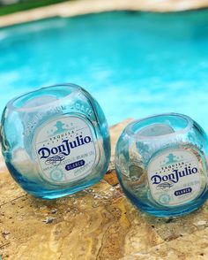 two empty bottles sitting next to a swimming pool