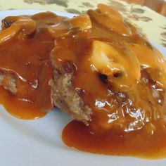 a white plate topped with meat and gravy covered in sauce on top of a table