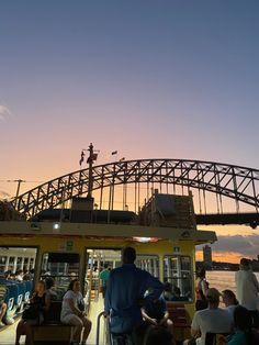 people are sitting and standing on the deck of a boat as the sun goes down