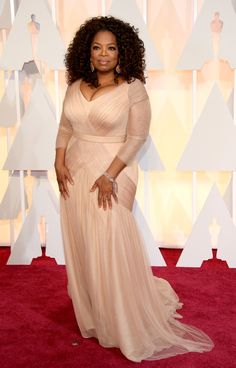 opi at the oscars wearing a nude colored gown with long sleeves and an open back