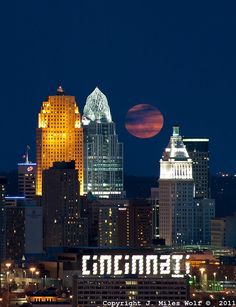 the full moon is seen over city lights