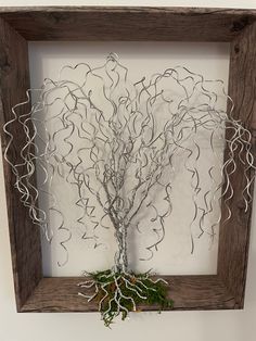 a wire tree in a wooden frame on the wall