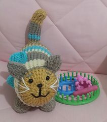 a crocheted cat toy next to a plastic comb and hair brush on a pink couch