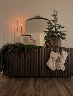 stockings and christmas decorations are hanging on the mantle in front of a mirror with candles