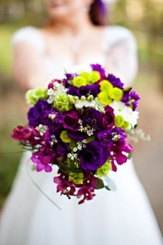 a bride holding a bouquet of purple and green flowers