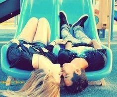 two people laying on top of each other in front of a slide at a playground