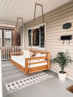 a porch swing sitting on top of a wooden floor next to a potted plant