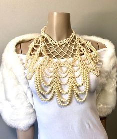 "Pretty faux pearl necklace with all over beads to dress up any look. Beads create a cross cross and drape loop design down the front. Adjustable clasp and chain in gold toned and variety of size beads Measurements: Bib front is 10\" long by 10\" to 5\" wide from top to bottom" Elegant Cream Beaded Bridal Necklace, Beaded Choker Bib Necklace For Wedding, Elegant Beaded Bib Necklace For Evening, Gold Beaded Pearl Necklace For Evening, Beaded Pearl Bridal Necklace For Party, Elegant Bib Necklace With Beaded Chain, Party Pearl Beaded Necklaces With Gold Beads, Party Pearl Beaded Necklace With Gold Beads, Cream-colored Pearl Chain Necklace For Party