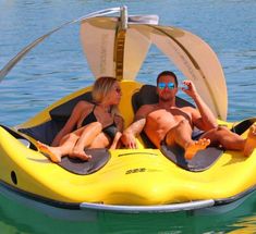 a man and woman laying on top of a yellow boat