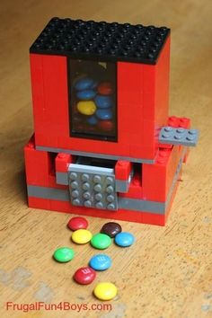 a lego machine with lots of candy in front of it on a wooden table top